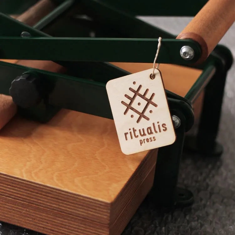 Wooden logo of the company Ritualis Press hanging on a lino press