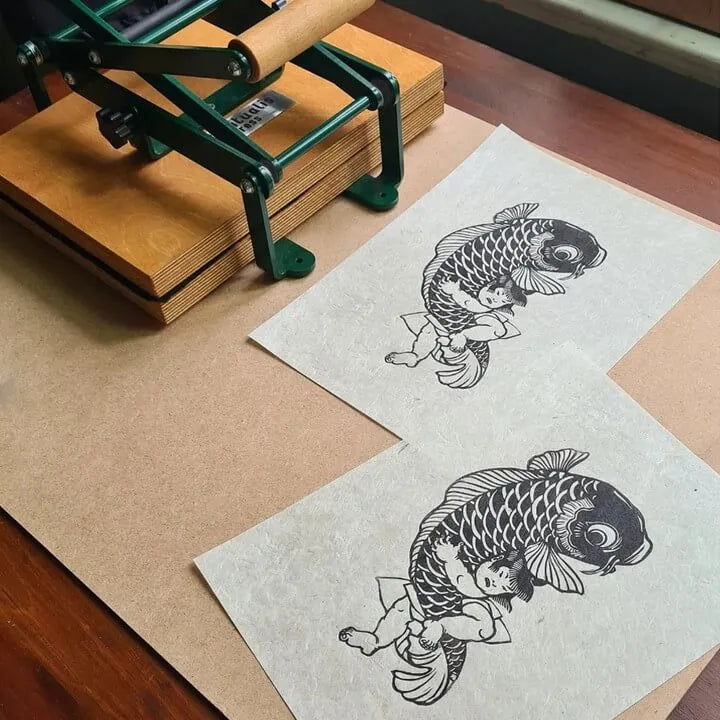Two A4 papers printed on a portable linocut press
