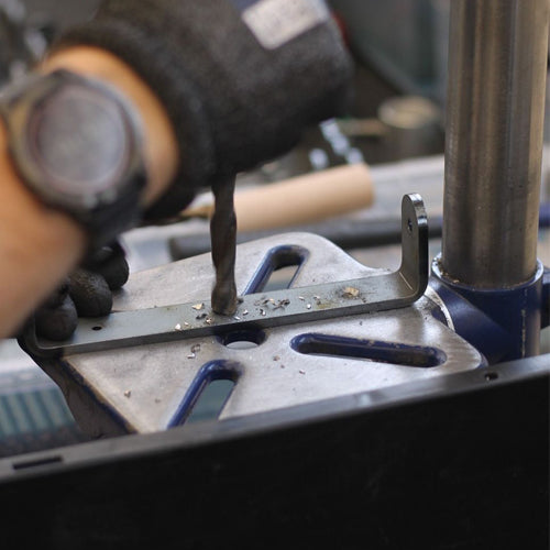 a hand holding a drill while creating a lino press